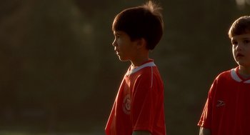 Movie still from “One Hour Photo” (2002), directed by Mark Romanek – A young boy in a red shirt is looking ahead; Close Up shot, Over the shoulder angle