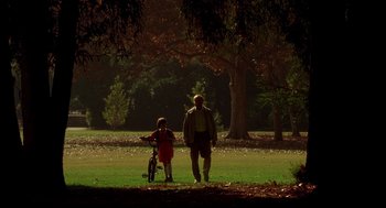 Movie still from “One Hour Photo” (2002), directed by Mark Romanek – A man and a child walking in a park; Extreme Wide shot, Low angle