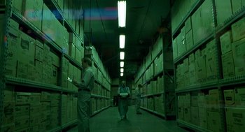 Movie still from “One Hour Photo” (2002), directed by Mark Romanek – Two men are walking through a warehouse filled with boxes; Wide shot, High angle