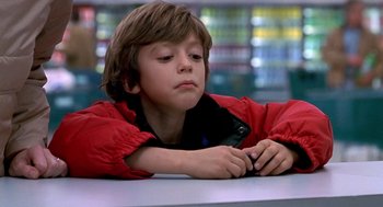 Movie still from “One Hour Photo” (2002), directed by Mark Romanek – A young boy in a red jacket looking at his cell phone; Close Up shot, Low angle