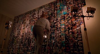 Movie still from “One Hour Photo” (2002), directed by Mark Romanek – A woman standing in front of a wall covered in pictures; Extreme Wide shot, High angle