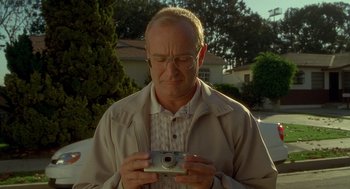 Movie still from “One Hour Photo” (2002), directed by Mark Romanek – An older man is holding a camera in his hands; Close Up shot, Low angle