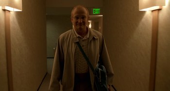 Movie still from “One Hour Photo” (2002), directed by Mark Romanek – A man with a beard is standing in an exit way; Medium shot, Low angle