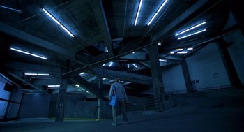 Movie still from “One Hour Photo” (2002), directed by Mark Romanek – A man standing in a parking garage at night; Extreme Wide shot, Low angle