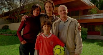 Movie still from “One Hour Photo” (2002), directed by Mark Romanek – A family posing for a picture with a soccer ball; Medium shot, Low angle
