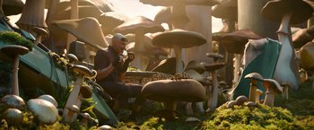 Movie still from “Sonic the Hedgehog 2” (2022), directed by Jeff Fowler – A man sitting in a field of mushrooms and drinking a cup of coffee; Wide shot, Low angle