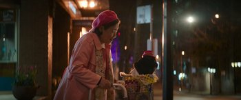 Movie still from “Sonic the Hedgehog 2” (2022), directed by Jeff Fowler – An older woman riding a bike past a basket full of flowers; Close Up shot, Over the shoulder angle