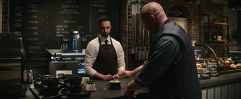 Movie still from “Sonic the Hedgehog 2” (2022), directed by Jeff Fowler – A man in an apron standing in front of a counter; Medium shot, Over the shoulder angle