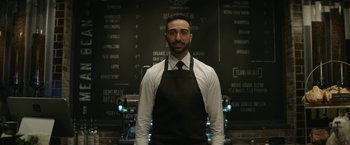 Movie still from “Sonic the Hedgehog 2” (2022), directed by Jeff Fowler – A man wearing a black apron standing in front of a menu board; Medium shot, Low angle