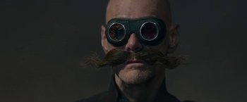 Movie still from “Sonic the Hedgehog 2” (2022), directed by Jeff Fowler – A bald man wearing a pair of goggles and a fake mustache; Close Up shot, Low angle
