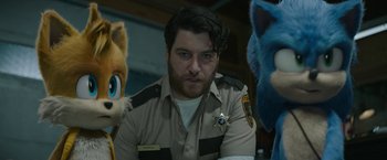 Movie still from “Sonic the Hedgehog 2” (2022), directed by Jeff Fowler – A man in a sheriff's uniform with some furry characters; Medium shot, Over the shoulder angle