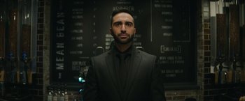 Movie still from “Sonic the Hedgehog 2” (2022), directed by Jeff Fowler – A man wearing a suit and tie standing in front of a wall; Close Up shot, Low angle