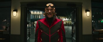 Movie still from “Sonic the Hedgehog 2” (2022), directed by Jeff Fowler – A man in a red and black jacket with a mustache; Medium shot, Over the shoulder angle