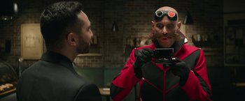 Movie still from “Sonic the Hedgehog 2” (2022), directed by Jeff Fowler – A man with a fake mustache taking a picture of himself in the mirror; Medium shot, Over the shoulder angle