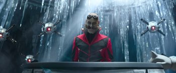 Movie still from “Sonic the Hedgehog 2” (2022), directed by Jeff Fowler – A man in a red and black jacket with a beard and sunglasses; Medium shot, Low angle