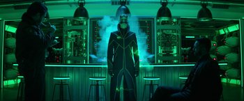 Movie still from “Sonic the Hedgehog 2” (2022), directed by Jeff Fowler – A man in a black suit standing in front of a green light; Medium shot, Low angle