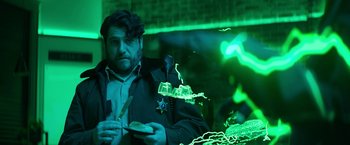 Movie still from “Sonic the Hedgehog 2” (2022), directed by Jeff Fowler – A man eating a sandwich in front of a green light; Medium shot, Over the shoulder angle