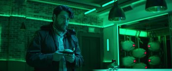 Movie still from “Sonic the Hedgehog 2” (2022), directed by Jeff Fowler – A man standing in front of a green lit wall; Medium shot, Low angle