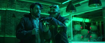 Movie still from “Sonic the Hedgehog 2” (2022), directed by Jeff Fowler – Two men are playing a video game in a green room; Medium shot, Over the shoulder angle