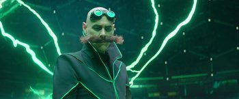 Movie still from “Sonic the Hedgehog 2” (2022), directed by Jeff Fowler – A bald man with a mustache and goggles; Medium shot, Low angle