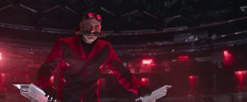 Movie still from “Sonic the Hedgehog 2” (2022), directed by Jeff Fowler – A man in a red jacket and goggles holding a white object; Medium shot, Low angle