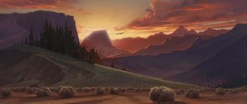 An eagle flying over a mountain range at sunset