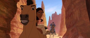 Movie still from “Spirit: Stallion of the Cimarron” (2002), directed by Lorna Cook – An animated scene of a man riding a horse and a woman riding a horse; Close Up shot, Over the shoulder angle