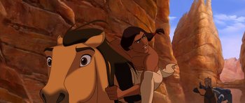 Movie still from “Spirit: Stallion of the Cimarron” (2002), directed by Lorna Cook – A man riding on the back of a horse in a cave; Medium shot, Low angle