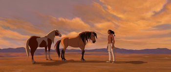Movie still from “Spirit: Stallion of the Cimarron” (2002), directed by Lorna Cook – A man standing next to two horses in a field; Wide shot, Low angle