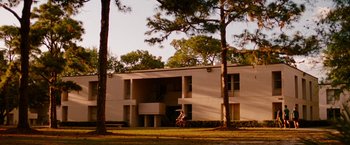 Movie still from “Spring Breakers” (2012), directed by Harmony Korine – A person riding a bike in front of an apartment building; Extreme Wide shot, Low angle