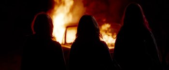 Movie still from “Spring Breakers” (2012), directed by Harmony Korine – A group of people sitting in front of a fire; Medium shot, Over the shoulder angle