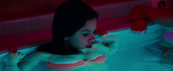 Movie still from “Spring Breakers” (2012), directed by Harmony Korine – A woman is laying in a pool of water at night; Medium shot, High angle