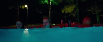 Movie still from “Spring Breakers” (2012), directed by Harmony Korine – A woman laying in a swimming pool at night; Medium shot, Low angle