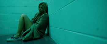 Movie still from “Spring Breakers” (2012), directed by Harmony Korine – A woman wrapped in a blanket sitting against a wall; Medium shot, High angle