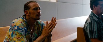 Movie still from “Spring Breakers” (2012), directed by Harmony Korine – A man sitting on a bench clapping his hands; Close Up shot, Over the shoulder angle