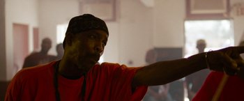 Movie still from “Spring Breakers” (2012), directed by Harmony Korine – A man in an orange shirt is pointing to the ceiling; Close Up shot, Low angle