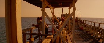 Movie still from “Spring Breakers” (2012), directed by Harmony Korine – A group of people standing on top of a wooden pier; Extreme Wide shot, High angle