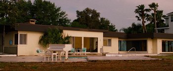 Movie still from “Spring Breakers” (2012), directed by Harmony Korine – An outside view of a house with a piano outside of the house; Extreme Wide shot, Low angle