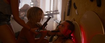 Movie still from “Spring Breakers” (2012), directed by Harmony Korine – A man and a woman are holding guns in their mouth; Medium shot, Low angle