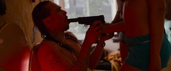 Movie still from “Spring Breakers” (2012), directed by Harmony Korine – A man with a gun in his mouth and a woman holding a gun; Medium shot, High angle