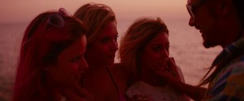Movie still from “Spring Breakers” (2012), directed by Harmony Korine – Three beautiful young ladies sitting next to each other on the beach; Close Up shot, High angle
