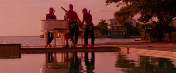 Movie still from “Spring Breakers” (2012), directed by Harmony Korine – A group of people sitting at a table near a body of water; Wide shot, High angle