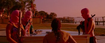 Movie still from “Spring Breakers” (2012), directed by Harmony Korine – A woman sitting at a table in front of a bottle of wine; Medium shot, Over the shoulder angle