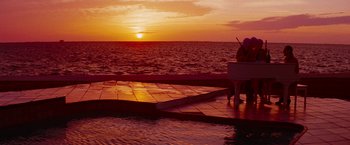 Movie still from “Spring Breakers” (2012), directed by Harmony Korine – A person standing next to the ocean at sunset; Extreme Wide shot, Over the shoulder angle