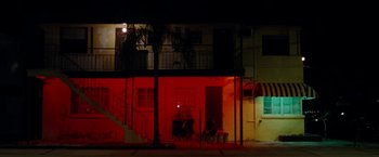 Movie still from “Spring Breakers” (2012), directed by Harmony Korine – Two people sitting on a bench in front of a building at night; Extreme Wide shot, Low angle