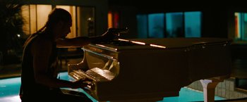 Movie still from “Spring Breakers” (2012), directed by Harmony Korine – A person is playing a piano in a dark room; Medium shot, Over the shoulder angle