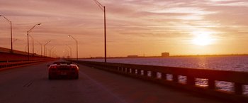 Movie still from “Spring Breakers” (2012), directed by Harmony Korine – A car driving down a road next to a body of water at sunset; Extreme Wide shot, Low angle