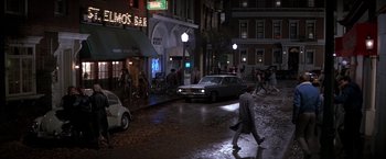 Movie still from “St. Elmo's Fire” (1985), directed by Joel Schumacher – A man walking down the street in the rain; Extreme Wide shot, High angle