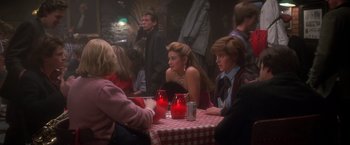 Movie still from “St. Elmo's Fire” (1985), directed by Joel Schumacher – A group of people sitting at a table with red candles; Medium shot, Over the shoulder angle