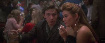 Movie still from “St. Elmo's Fire” (1985), directed by Joel Schumacher – A man and a woman sitting next to each other holding a cigarette; Close Up shot, Over the shoulder angle